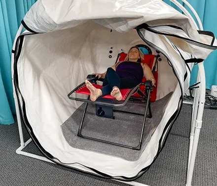 The Grand Dive Pro Plus unzipped at the front, with a woman resting in a reclining chair inside.