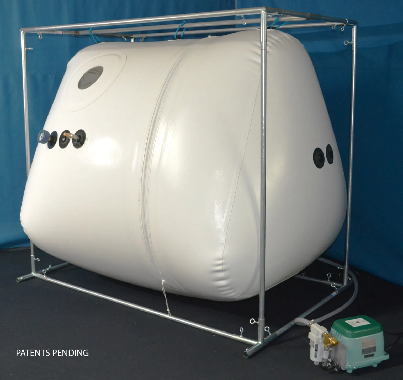 The Newtowne Chamber Tent, a tall white chamber with round windows, inside a square steel frame.